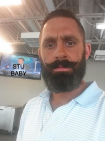 A man with a beard and mustache standing in front of a tv.